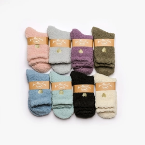 Flat lay of eight colorful coral fleece socks with gold heart embroidery and kraft packaging