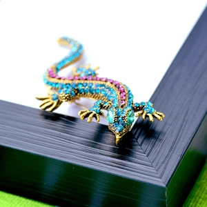 Macro view of lizard brooch with blue and pink rhinestones on a gold metal base