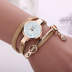 Detail of Yukas quartz watch with rhinestone charms and light beige wrap bracelet on wrist