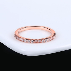 Elegant rose gold engagement ring with pavé-set zircons on a white surface