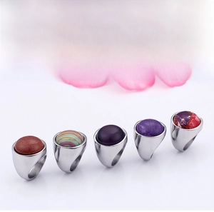 Close-up of five chunky stainless steel rings set with various colorful oval gemstones