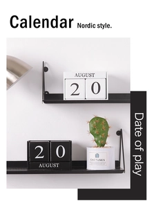 Détail d'un calendrier perpétuel nordique en bois affichant le 20 août sur une étagère noire
