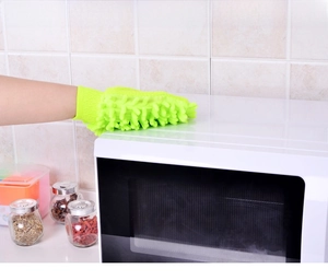 Vue détaillée d'un gant épais en chenille verte essuyant un micro-ondes de cuisine