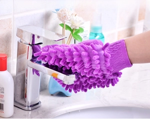 Détail d'un gant de lavage chenille violet nettoyant un robinet de salle de bain