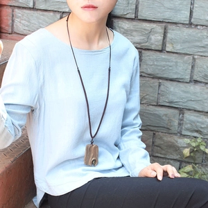 Close-up of a handmade wooden rectangle pendant with natural grain on a brown cord necklace