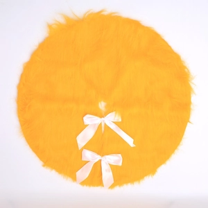 Detailed macro view of orange plush Christmas tree skirt with elegant white ribbon ties