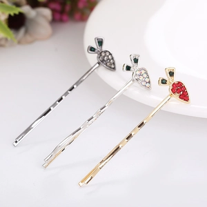 Close-up of golden carrot hair clips with sparkling rhinestones in black and red colors