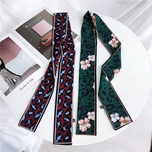 Double-sided leopard print twilly scarves in red-blue and green-pink floral on a table