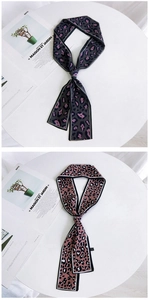 Vertical display of double-sided leopard print scarves on white table with fashion magazine