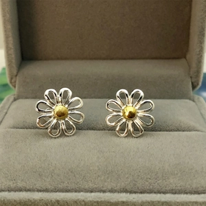Detailed macro view of daisy stud earrings with silver petals and golden center