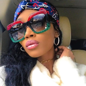 Detail of oversized square sunglasses featuring tricolor red, black, and green glitter frames