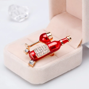 Detail of a gold wine bottle brooch with red enamel and sparkling rhinestones in a velvet box