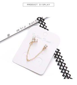Detail of gold chain earrings with sparkling rhinestones displayed on a fashion card