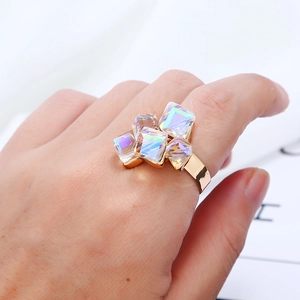 Dettaglio dell'anello geometrico dorato con cinque cristalli cangianti sul dito della mano