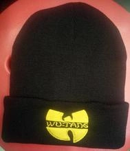 Close-up of yellow Wu-Tang logo embroidery on a black knit beanie hat with folded brim