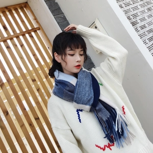 Detailed close-up of thick plaid knit scarf with blue and grey tassels in outdoor setting