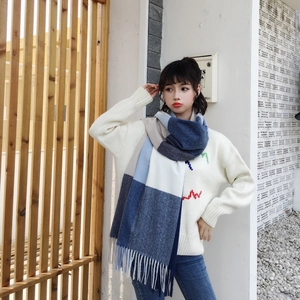 Detailed view of heavy-knit scarf with plaid pattern in blue and white and long fringe