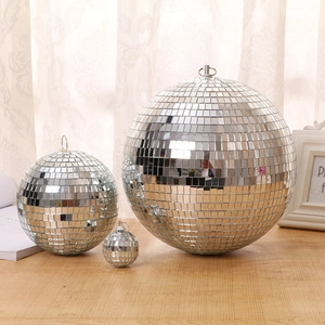 Three reflective glass disco balls of various sizes arranged on a rustic wooden table