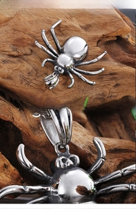 Polished silver spider pendant with detailed legs on dark wood background