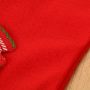 Close-up of red felt fabric texture with green and white holiday embroidery detail