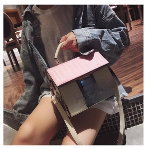 Detail of house-shaped crossbody bag with pink roof and window design on white wall