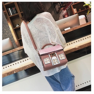 Close-up of a house-shaped crossbody bag featuring pink roof and detailed white door