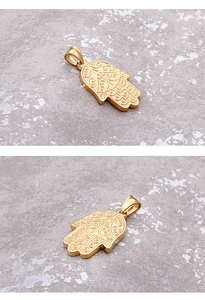 Detail of golden Hamsa Hand pendant with intricate swirl relief texture on metal surface