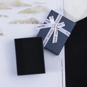 Navy textured paper jewelry gift box with a white silk ribbon and lid at a 45-degree angle