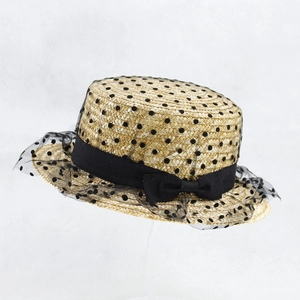 Detail of wheat straw hat featuring black bow ribbon and polka dot mesh veil accent