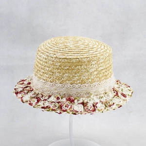 Detailed macro view of beige straw hat featuring elegant white lace and floral fabric trim