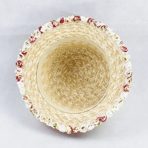 Top view of hand-woven straw hat with mini red and white rose floral trim detail