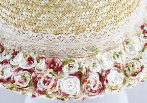 Detailed close-up of lace ribbon and red fabric roses on a straw sun hat