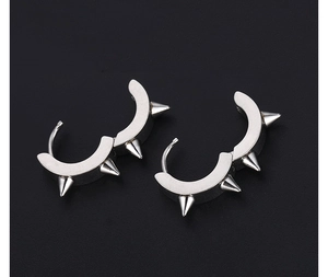 Macro detail of silver stainless steel spike earrings with punk rivet design on black