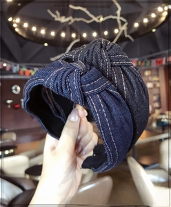 Close-up of deep blue denim knotted headband with orange contrast stitching detail