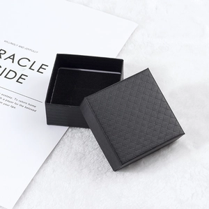 Detail of square black jewelry box with textured rhombus pattern and velvet lining