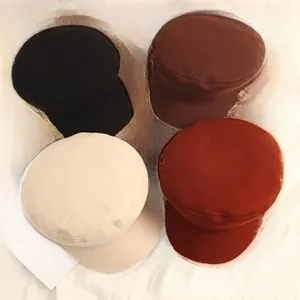 Flat lay of denim newsboy caps in black, brown, beige, and red colors on a white fabric