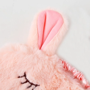 Close-up of pink plush sleeping mask with cute bunny ears and soft faux fur texture