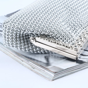 Elegant silver beaded evening clutch bag with sparkling rhinestone closure on a magazine