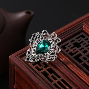 Macro shot of green teardrop gemstone and vintage silver hollow lace metalwork