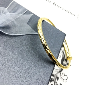 18K gold-plated adjustable bracelet with diamond-cut texture on a grey gift box