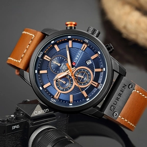 Close-up of blue chronograph watch dial with leather strap next to a vintage camera