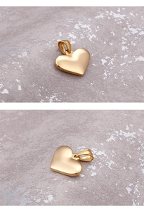 Close-up of a polished golden heart pendant on a textured grey surface with macro details