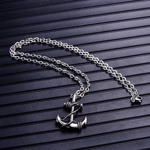 Macro detail of silver anchor pendant with rope texture on a dark textured background