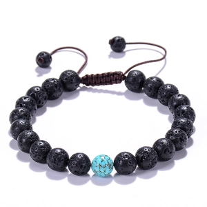 Detailed view of porous black lava stone bracelet with blue turquoise bead on white background