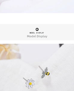Macro shot of asymmetrical daisy flower and bee stud earrings with zircon wings