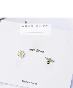 Detail of asymmetric daisy and bee studs with crystal wings on a white card