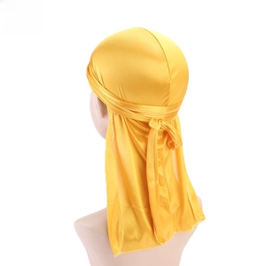 Detail of a bright yellow silky durag with long tail shown on a head model mannequin