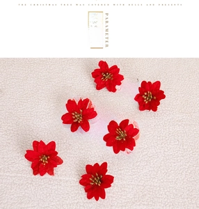 Detail of six artificial red Christmas flowers with gold stamens on beige fabric