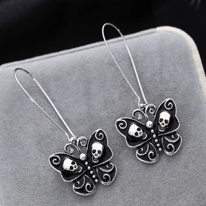 Macro shot of gothic butterfly drop earrings with black enamel and skull details