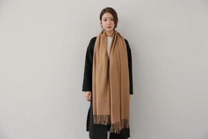 Detail of camel cashmere scarf featuring fine fringe edges and soft brushed texture